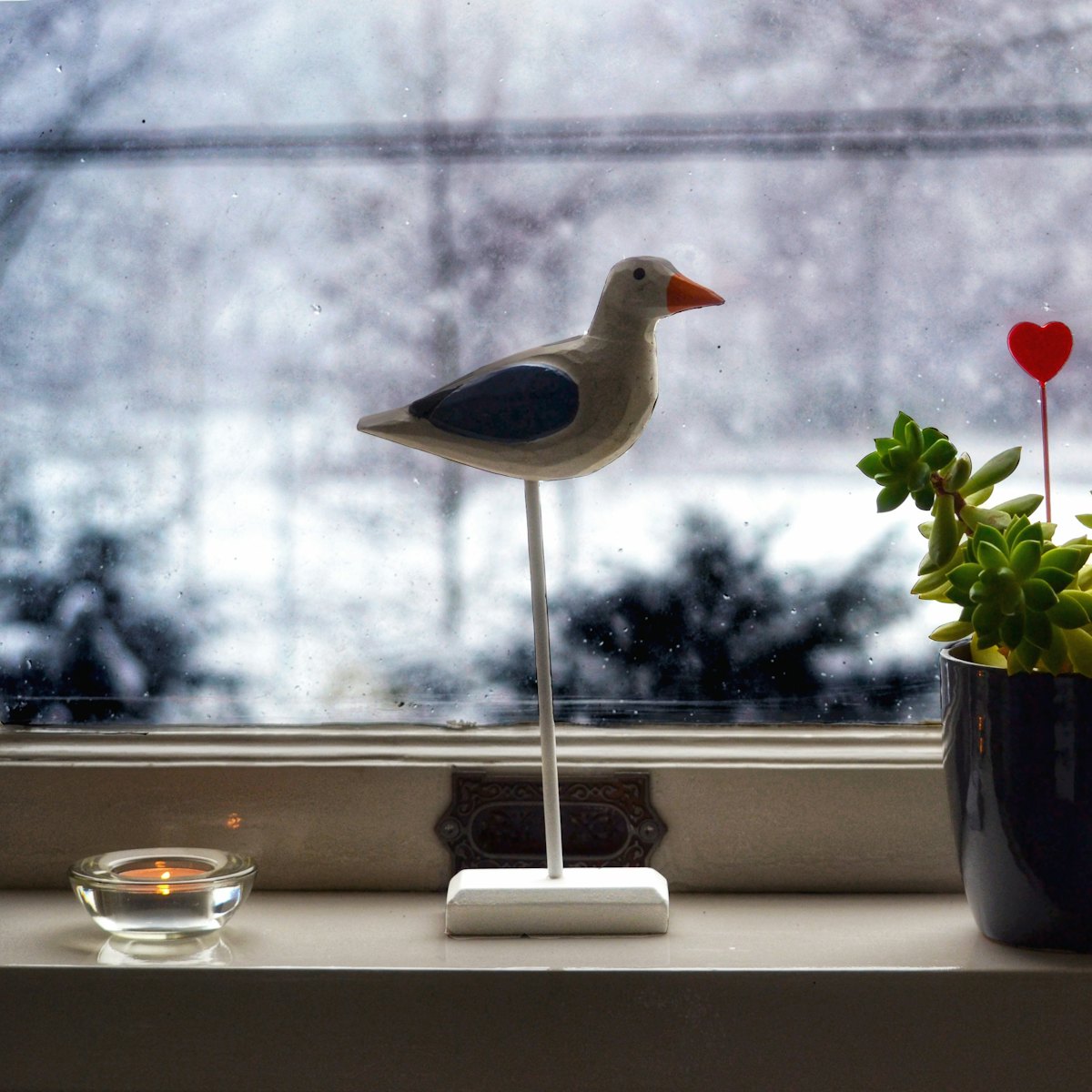 A small carved bird standing on a windowsill.